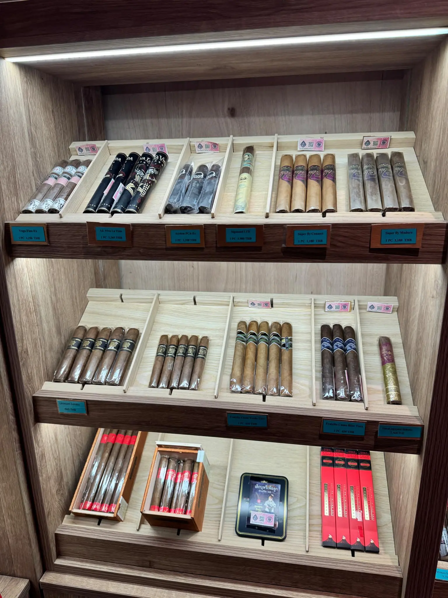 A selection of premium tobacco products displayed in a wooden display case at Cigar Emperor.