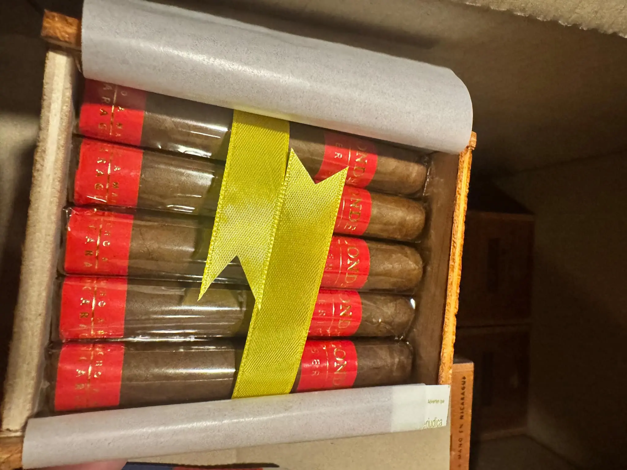 Condega products neatly arranged in an open wooden box, highlighting the red and gold bands and yellow ribbon.